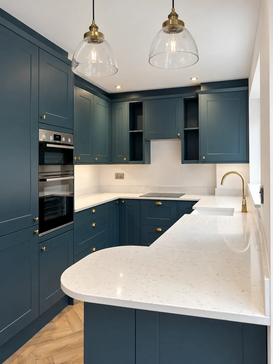 Blue shaker kitchen seen from the doorway, two glass pendants above a curved peninsula