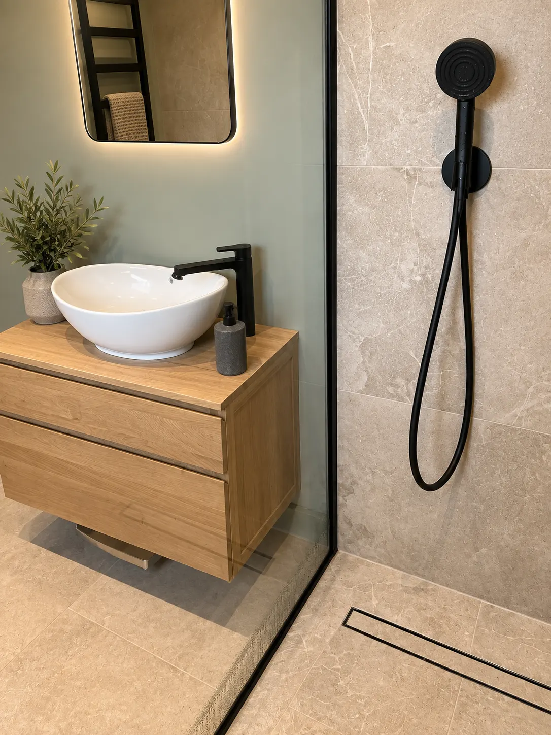 Oak wall-hung vanity with a vessel basin and matt black tap beside a black handheld shower